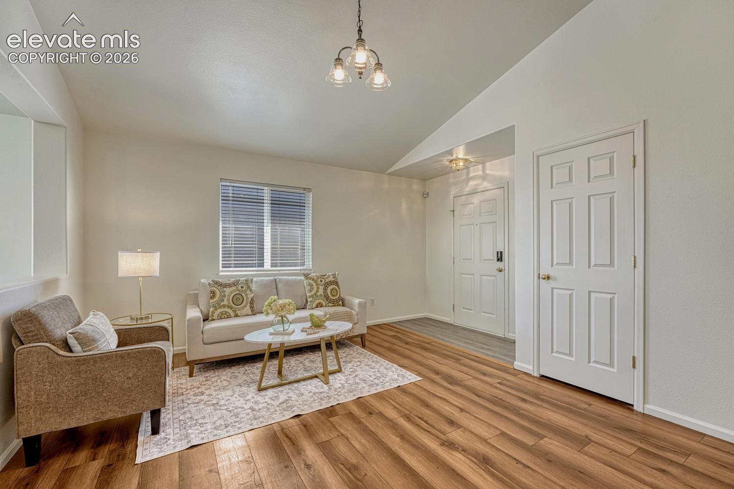 Spacious vaulted Living Room with LVP flooring, an attractive light fixture, and convenient coat closet.