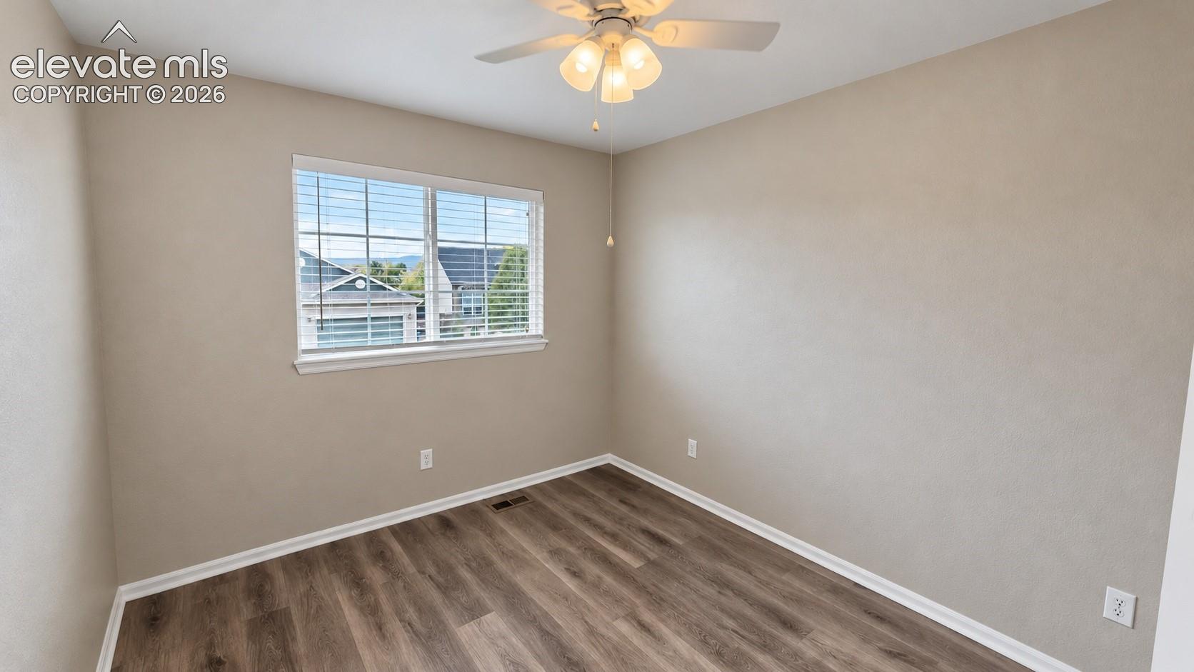 Neutral interior featuring wood-finish flooring, a multi-pane window, and a ceiling-mounted light fixture with a fan