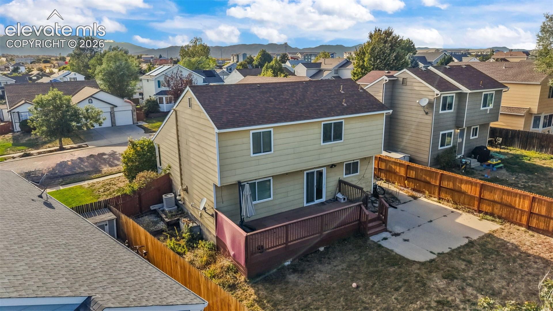 Two-story residence with siding exterior, brown shingle roof, and an elevated wood-finish deck