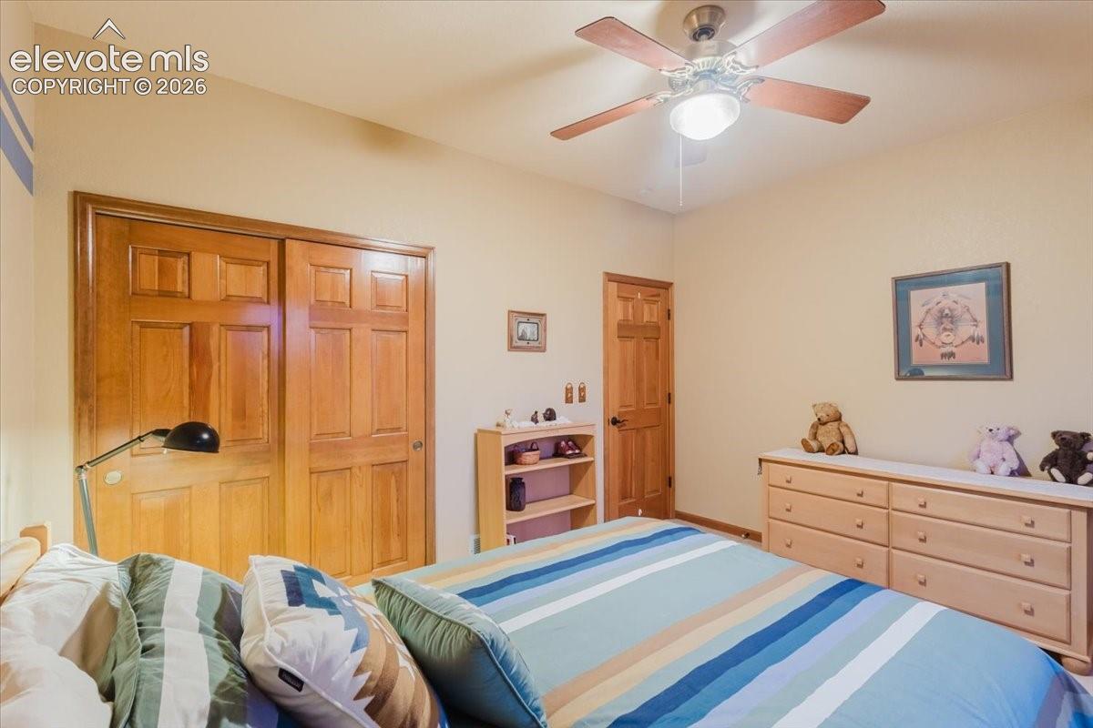 Bedroom featuring a ceiling fan, light-toned walls, and wood-finish doors