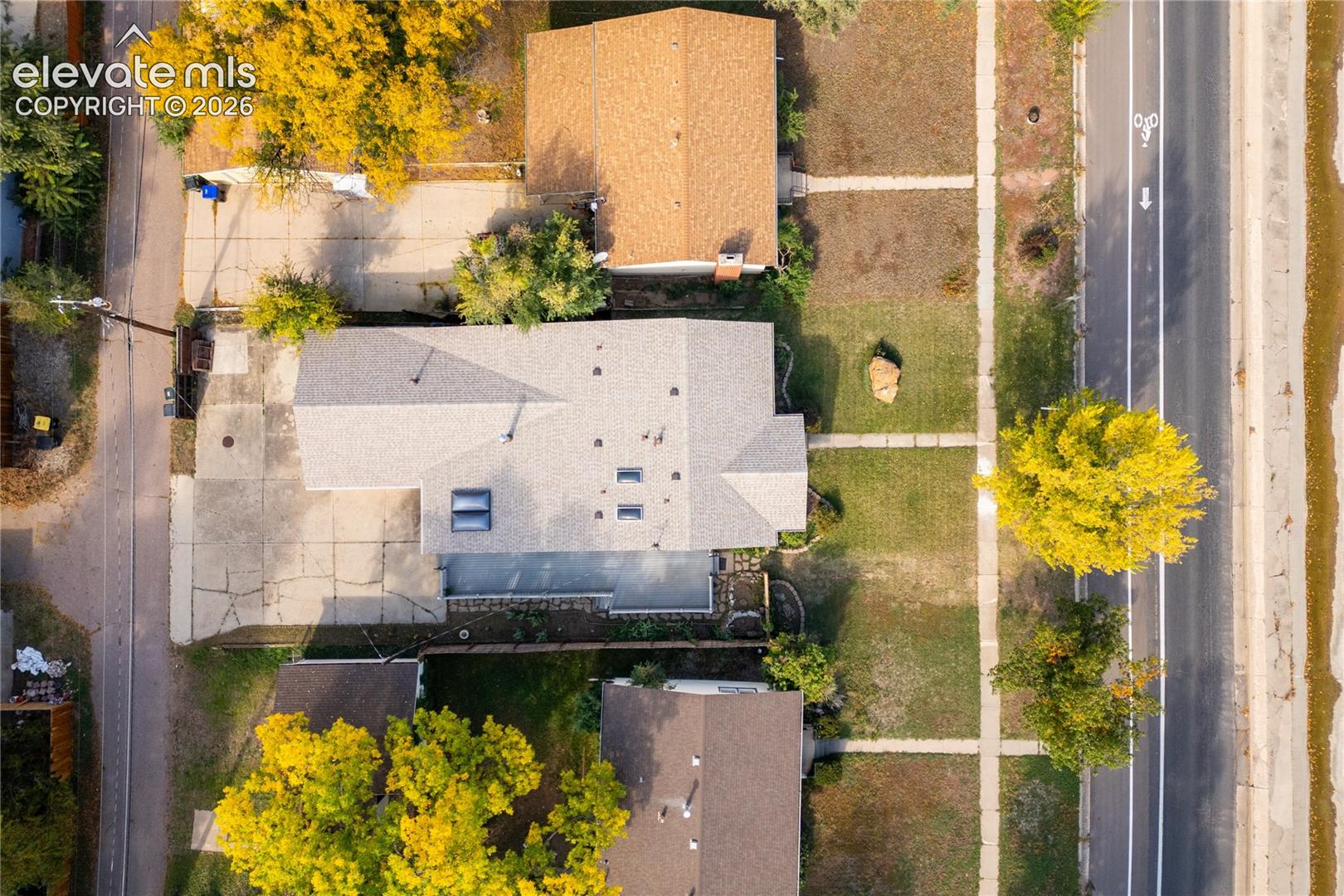 Single-story residence with a light gray shingle roof, multiple skylights, and a paved concrete driveway