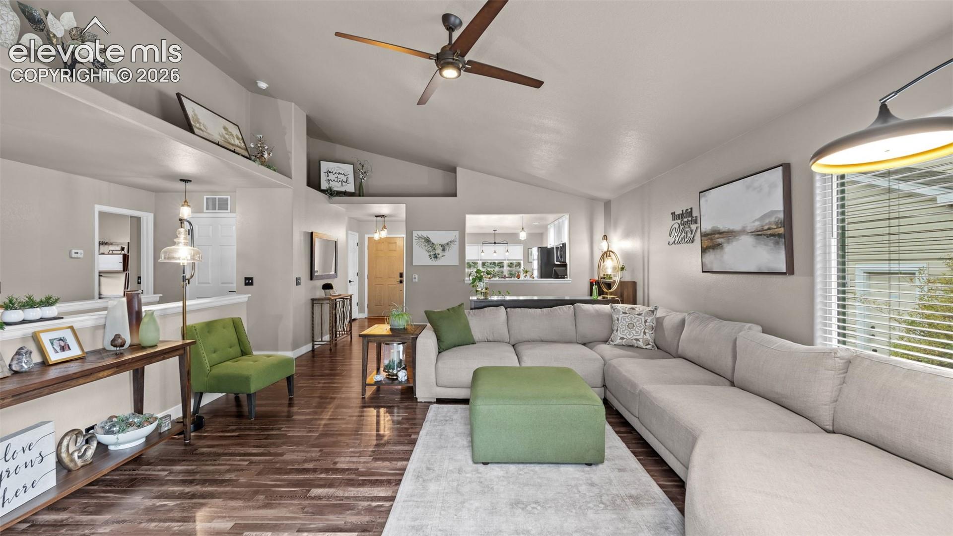 Vaulted ceilings, wood-finish flooring, recessed shelving, and a ceiling fan