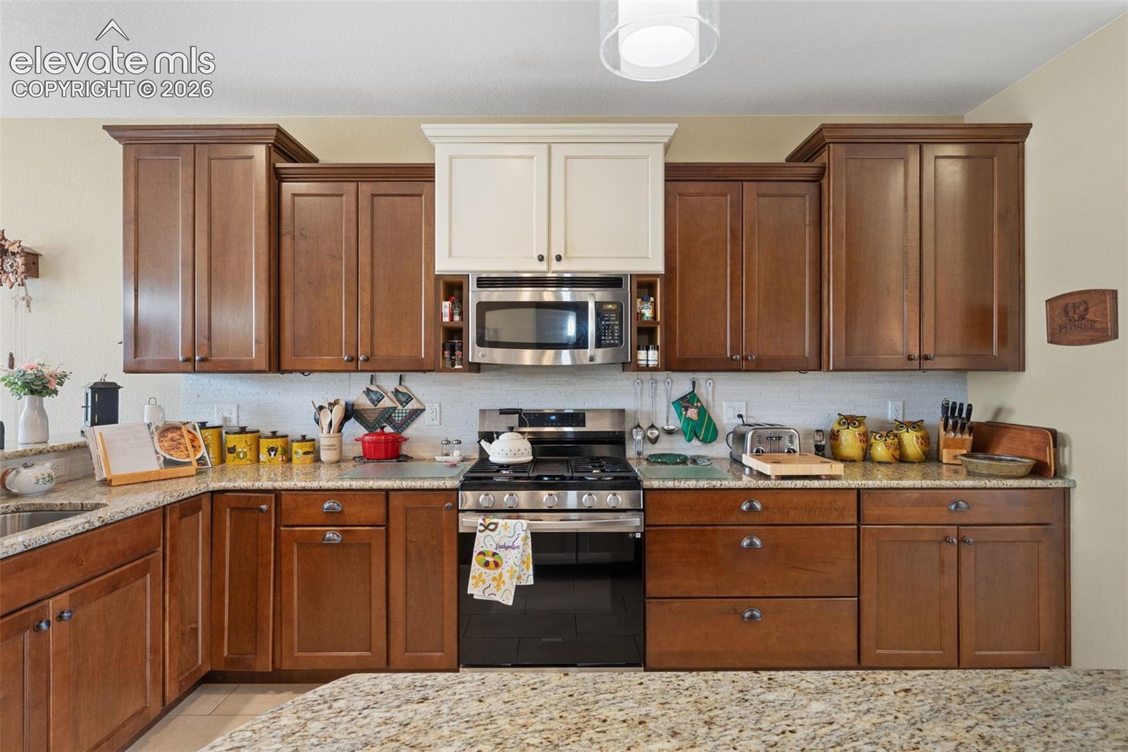 Well-appointed kitchen featuring a stainless steel gas range, built-in microwave, and ample wood cabinetry