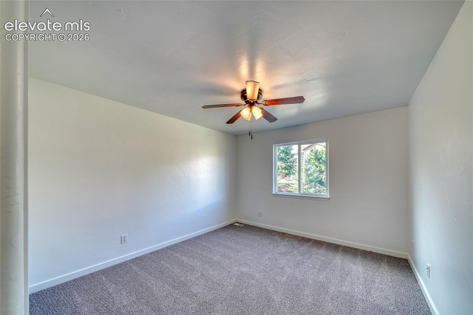 Neutral wall finishes, recessed window, ceiling fan with integrated lighting, and textured carpeting