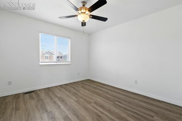Empty room featuring wood finished floors, baseboards, and a ceiling fan
