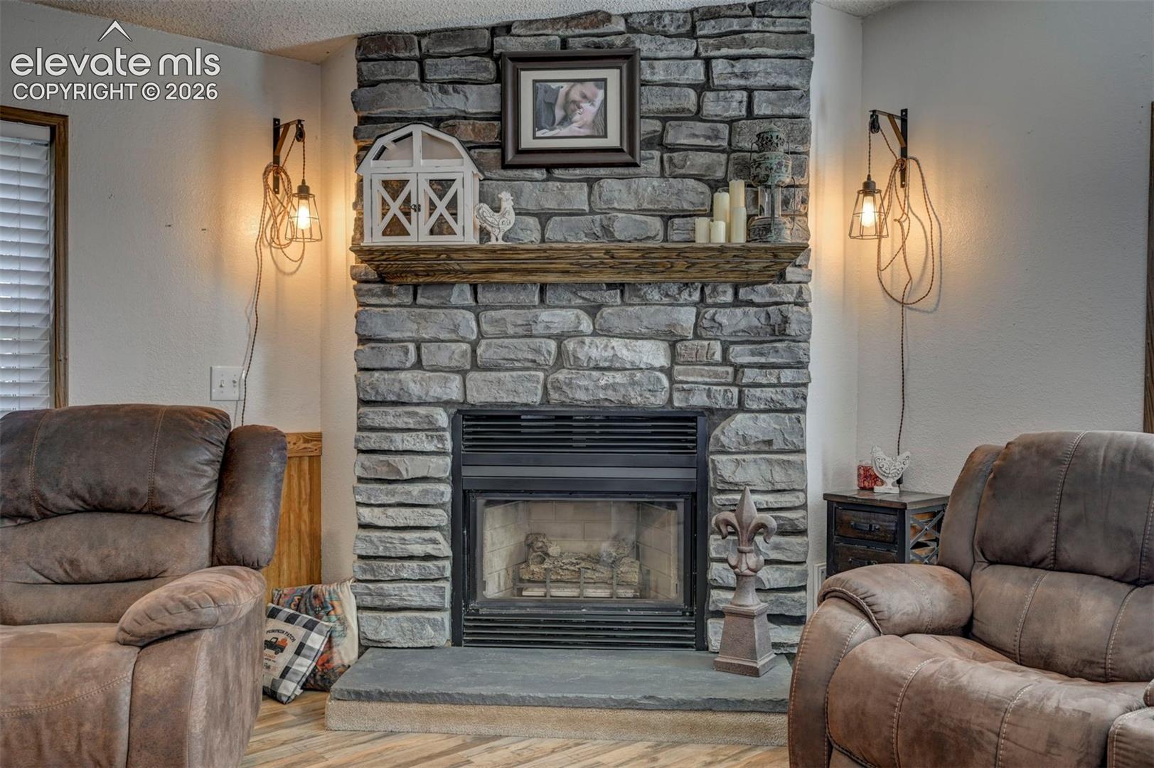 Living room featuring wood finished floors, a textured ceiling, a fireplace, and a textured wall