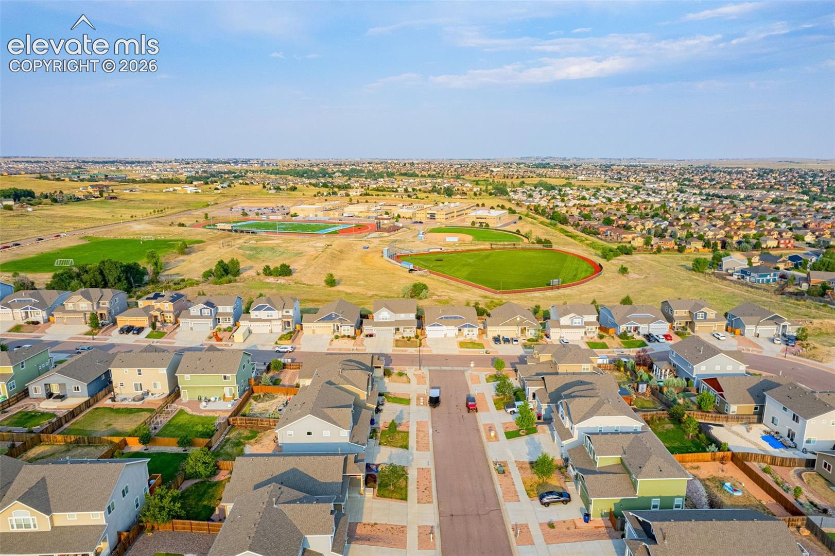 Residential development with varied architectural styles and integrated open spaces, featuring a community sports field and surrounding natural terrain