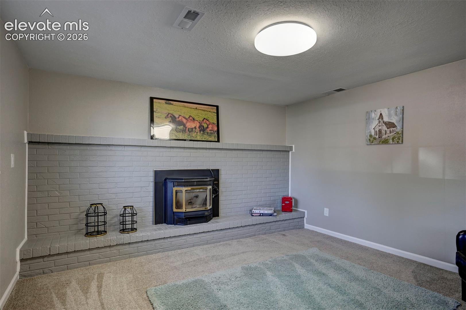 Painted brick fireplace surround featuring an elevated hearth and a built-in insert