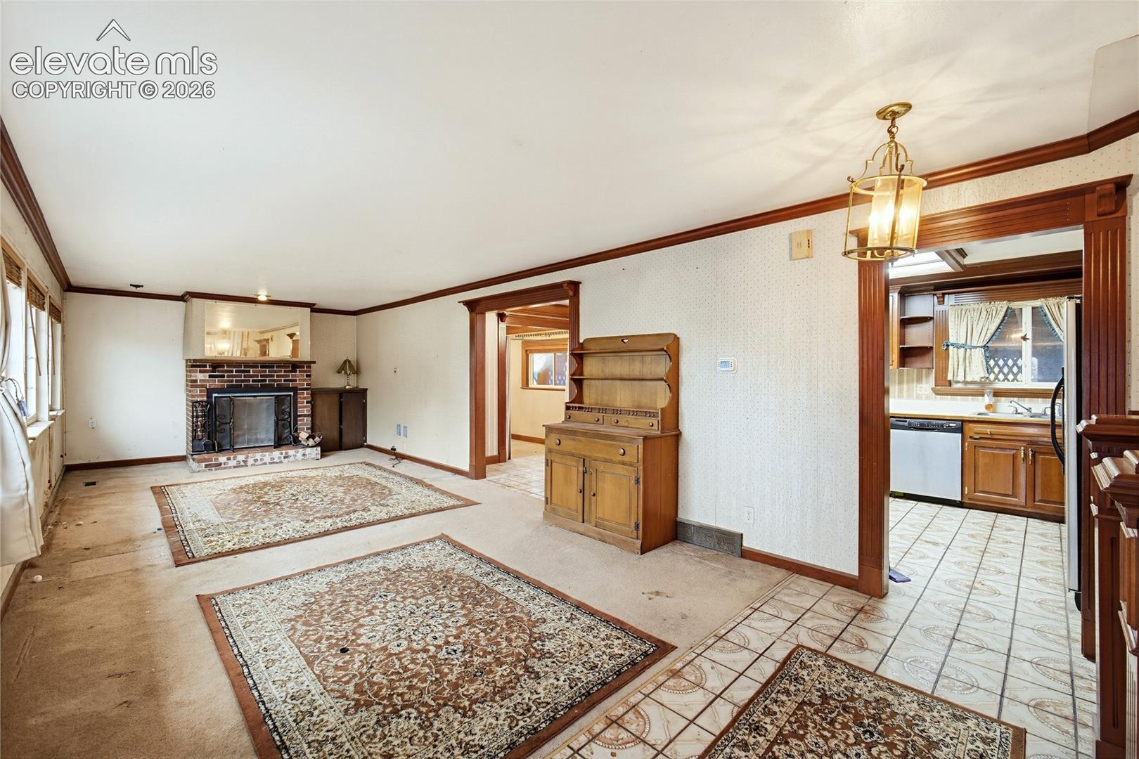 Brick fireplace with mirrored mantel, wood trim detailing, recessed window, and a brass-finish chandelier