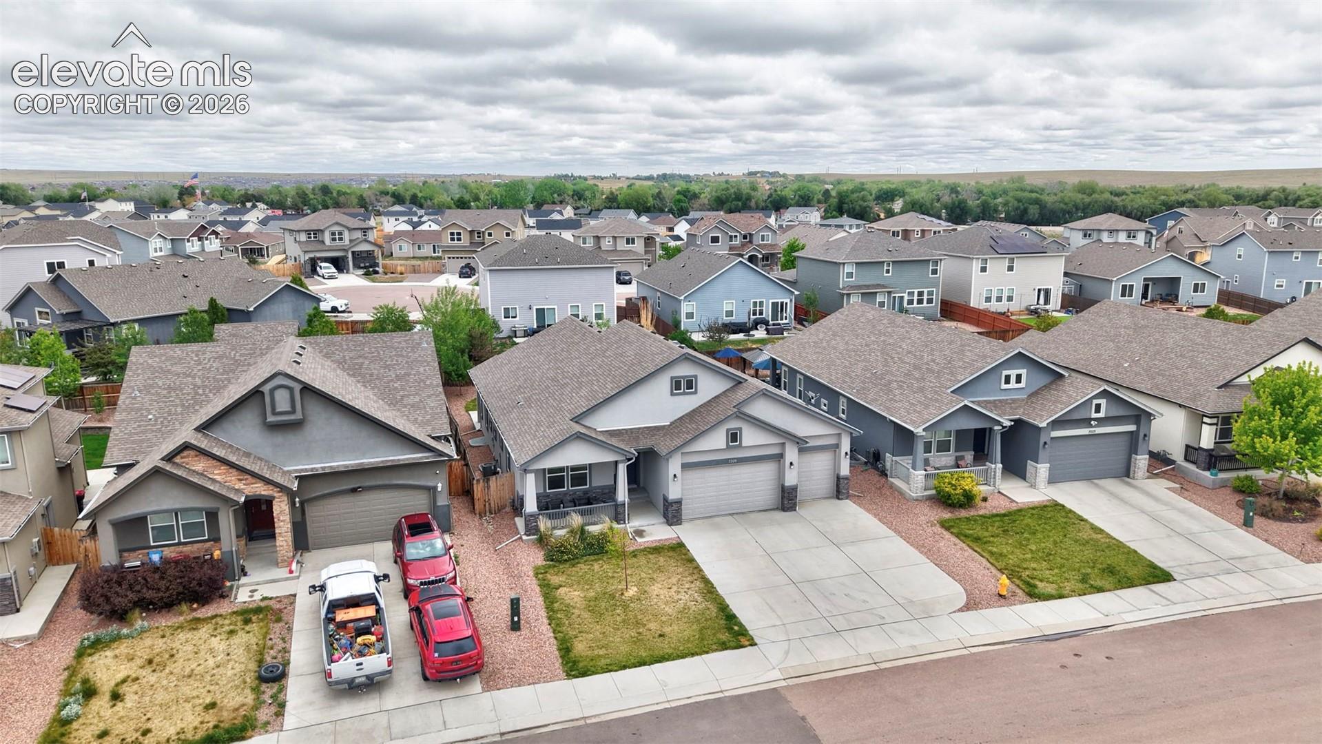 Aerial perspective of residential suburban neighborhood featuring varied architectural elevations, asphalt shingle roofs, concrete driveways, and stone-accented facades