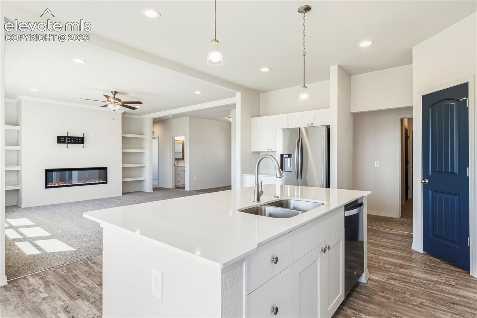 Kitchen island with dual stainless steel sink, white cabinetry, and quartz countertop