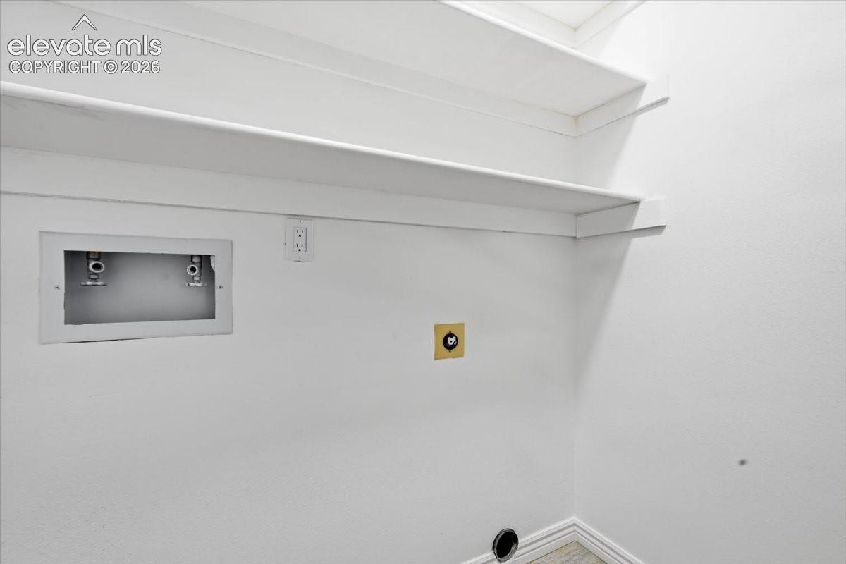 Built-in shelving, white painted walls, water hookups, electrical outlet, and floor drain