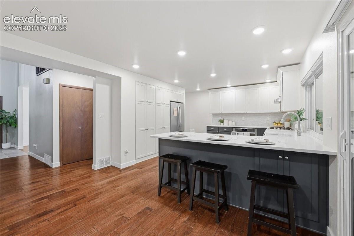 Kitchen featuring wood flooring, recessed lighting, white built in pantry and quartz countertops