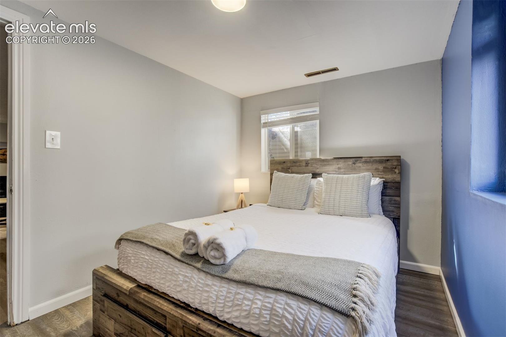 Wood-finish flooring, a window with horizontal blinds, and a built-in light fixture