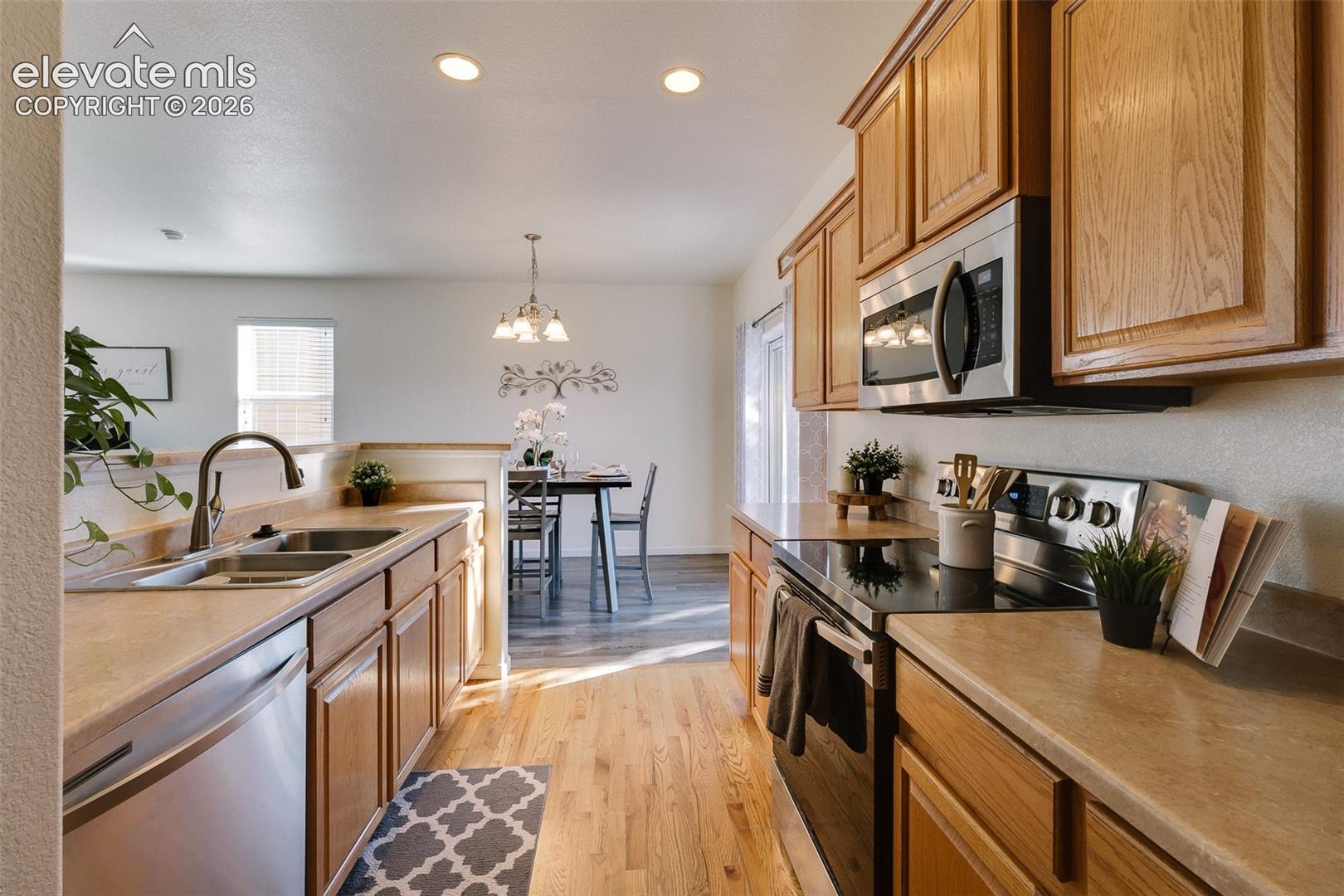 Kitchen with wood-finish flooring, recessed lighting, wood cabinetry, stainless steel appliances, and a double basin sink