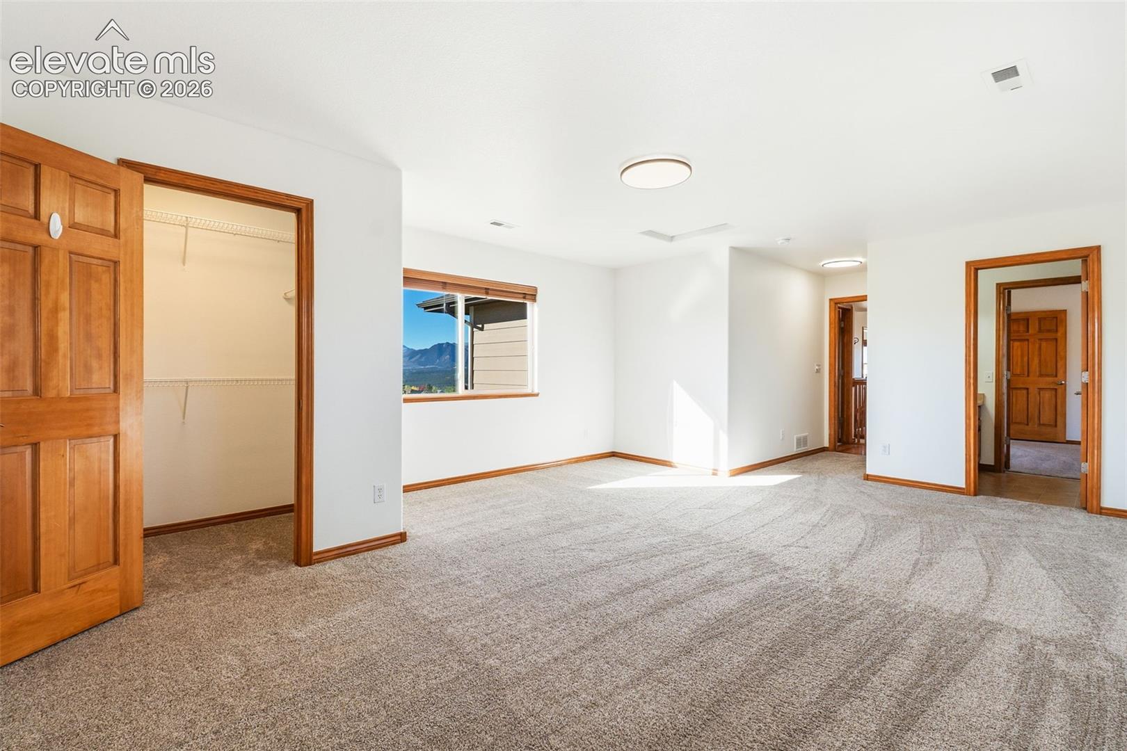 Spacious interior room featuring wall-to-wall carpeting, wood-finish interior doors, recessed lighting fixtures, and a window with mountain scenery