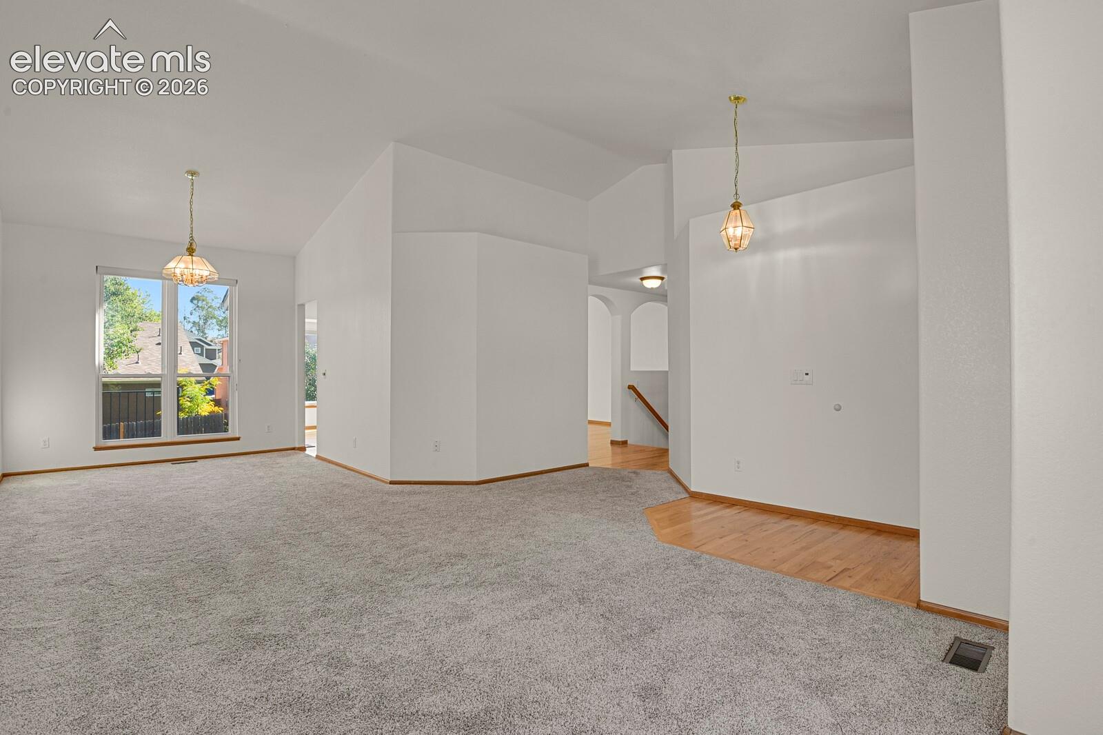 Vaulted ceilings, large window, carpet flooring, wood-finish flooring, and built-in lighting fixtures