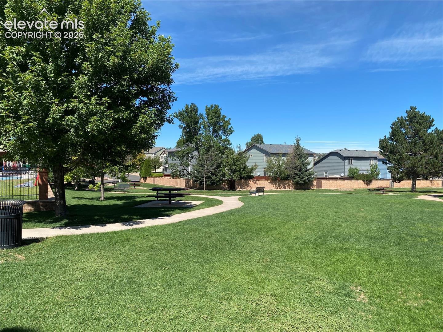 Wider view of the grassy lawn, some picnic areas, walking paths, benches.  Pool area to the left out of view.