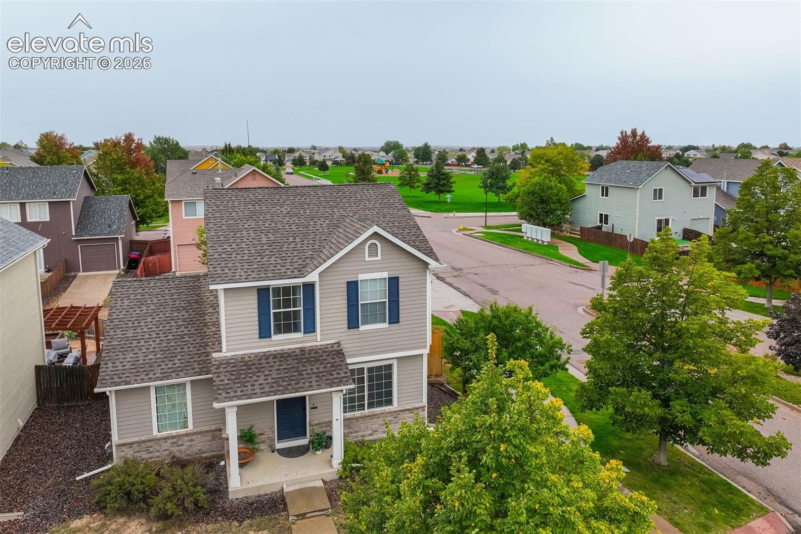 Two-story residence featuring a covered front porch, a two-car garage, and mature landscaping