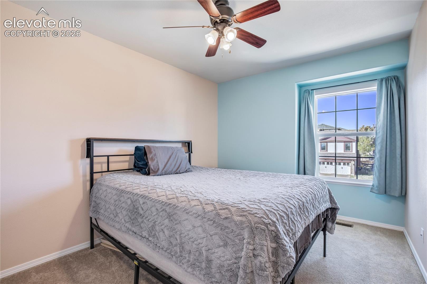 An additional upper-level bedroom features a ceiling fan, carpeting + natural light, completing the home's three-bedroom upper-level arrangement.