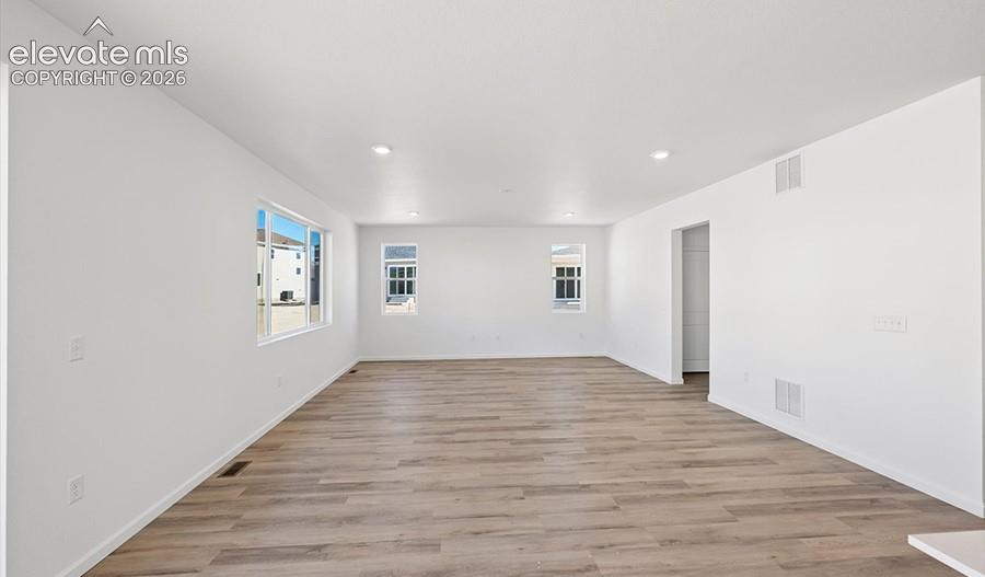 Neutral-toned interior space featuring wood-finish flooring, recessed lighting, and multiple windows
