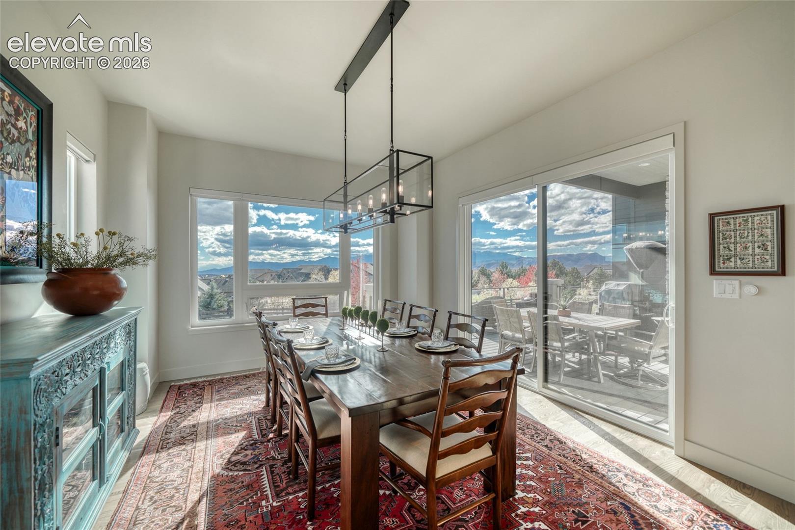Dining space featuring a linear metal chandelier, large-format windows, and sliding glass doors leading to an exterior balcony
