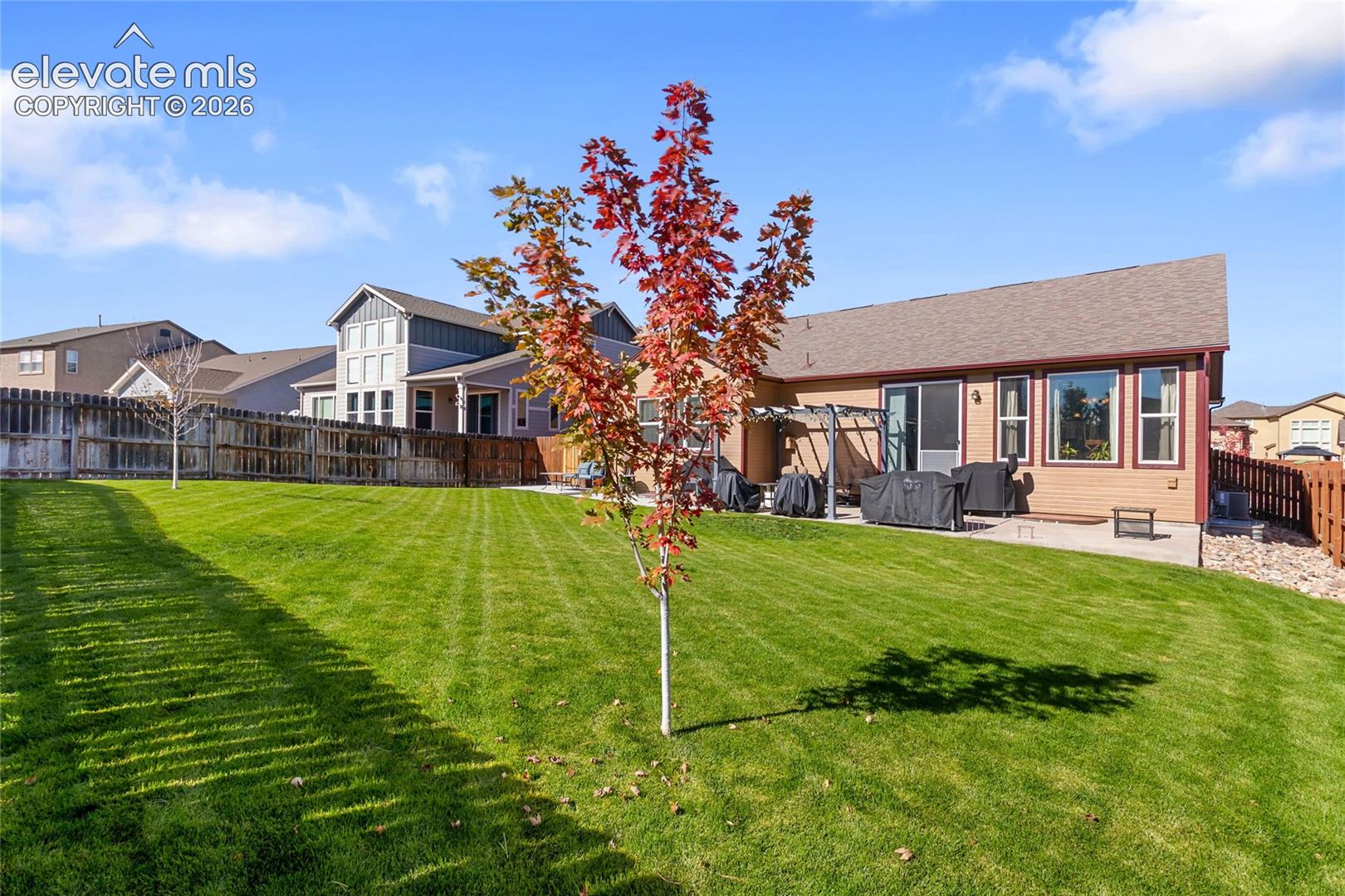 Backyard featuring a manicured lawn, concrete patio, wood fencing, and a decorative pergola