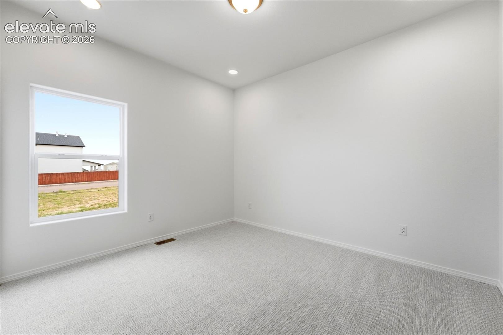Neutral-toned carpeting, recessed ceiling lighting, and a single-pane window with exterior landscape exposure