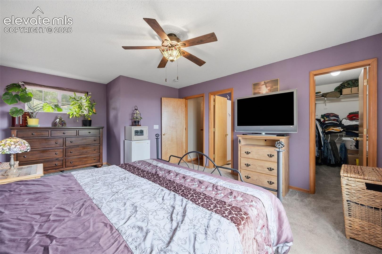 Primary Bedroom featuring a ceiling fan with light fixture, wood-trim window, and neutral carpeting