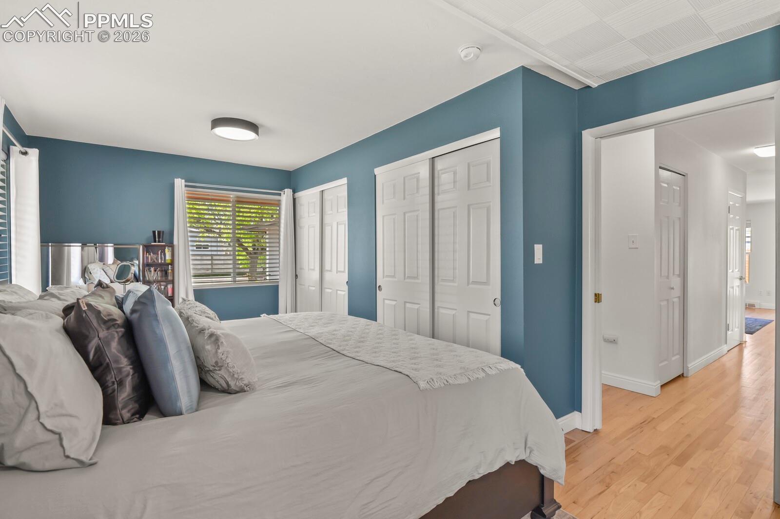 Spacious primary bedroom featuring hardwood flooring, double closets and multiple windows