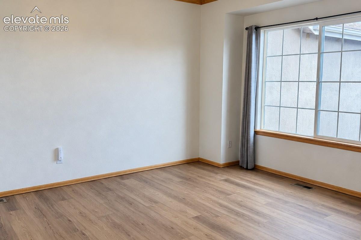 Wood-finish flooring with coordinating wood trim, large window with grid pattern, and neutral wall tones. No staging