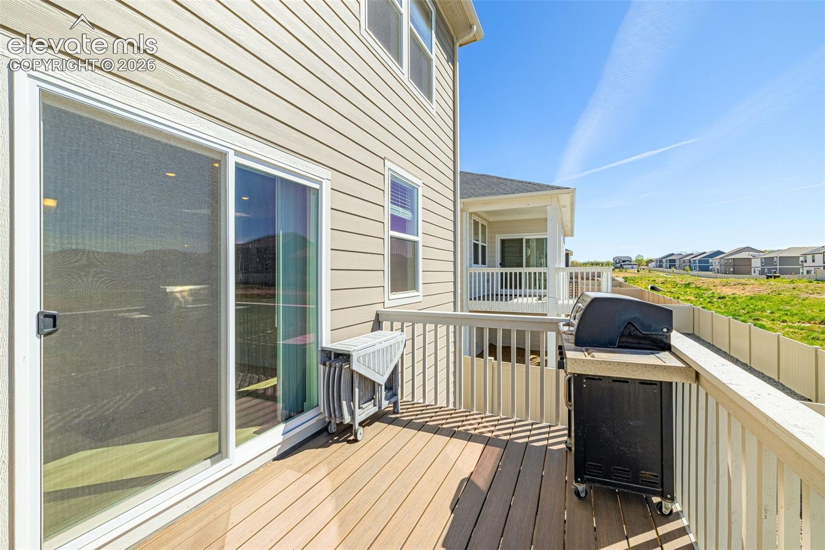 Exterior deck featuring wood-finish flooring, sliding glass door, and a privacy fence