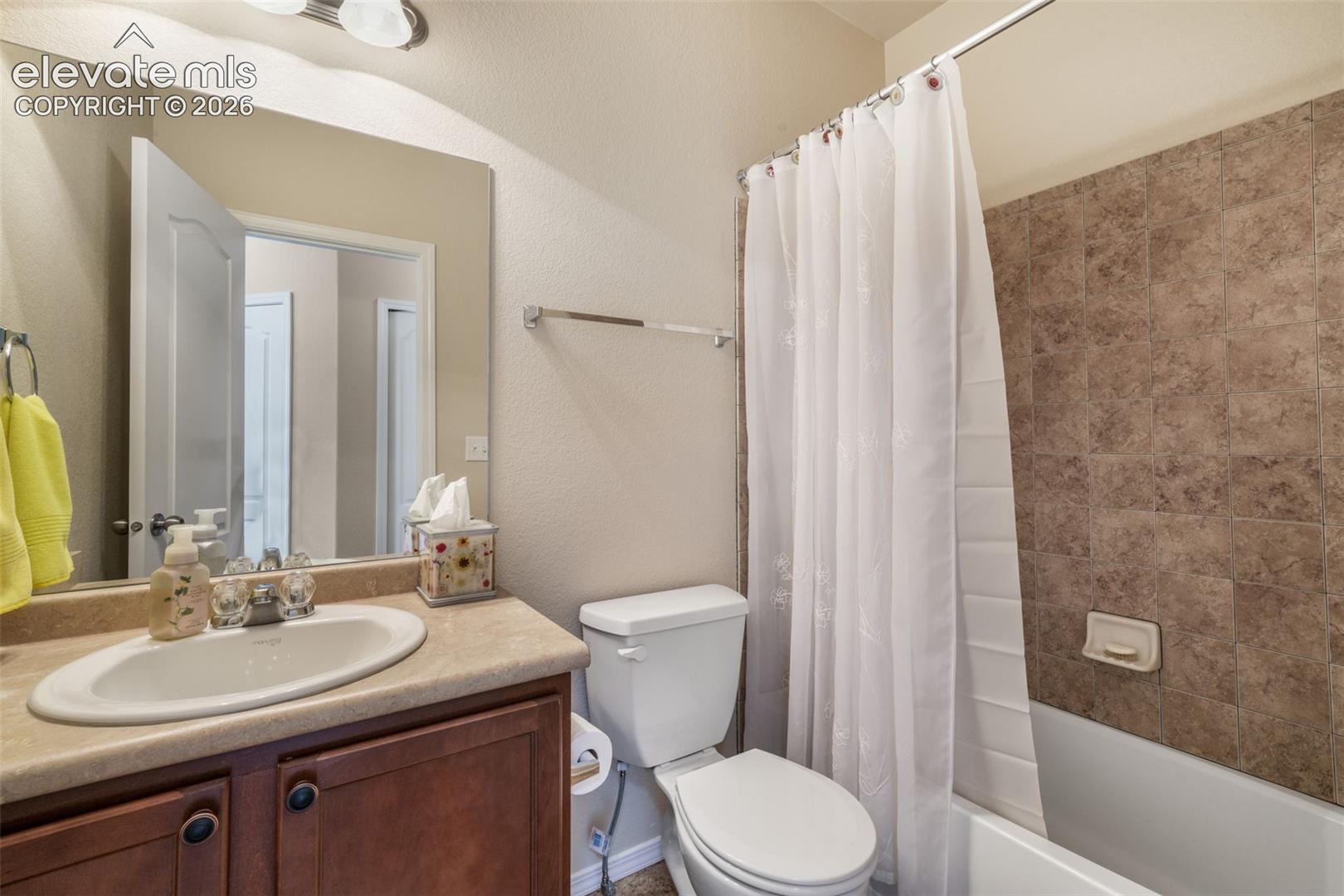 Vanity with an integrated sink, wood-finish cabinetry, and a neutral countertop