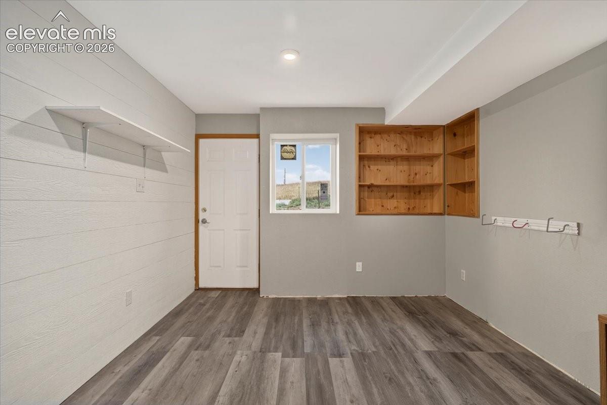 Wood-finish flooring, horizontal wall paneling, built-in natural wood shelving, and recessed ceiling lighting