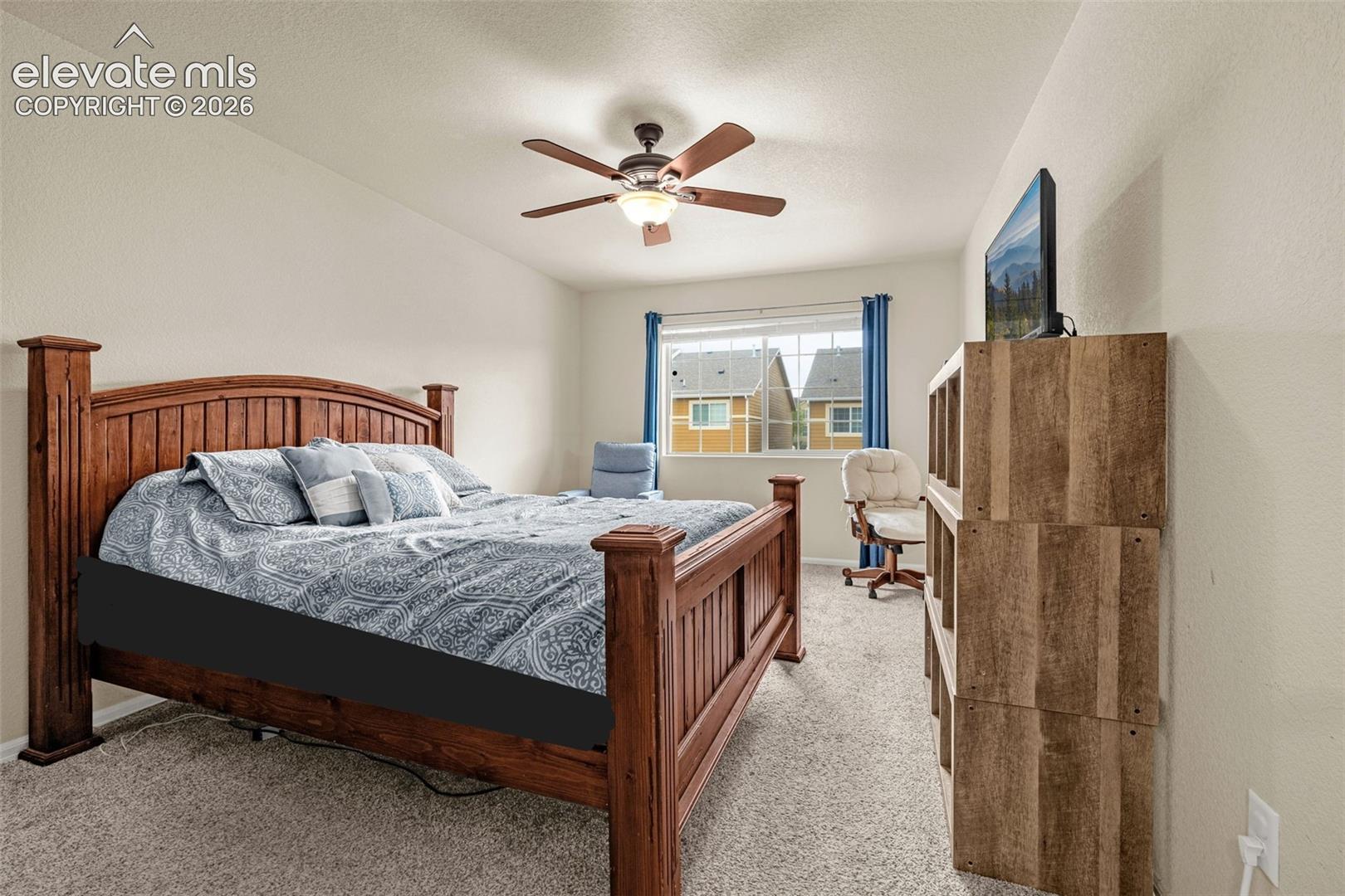 Carpeted flooring, vaulted ceiling, ceiling fan with integrated lighting, window with blinds, and built-in shelving