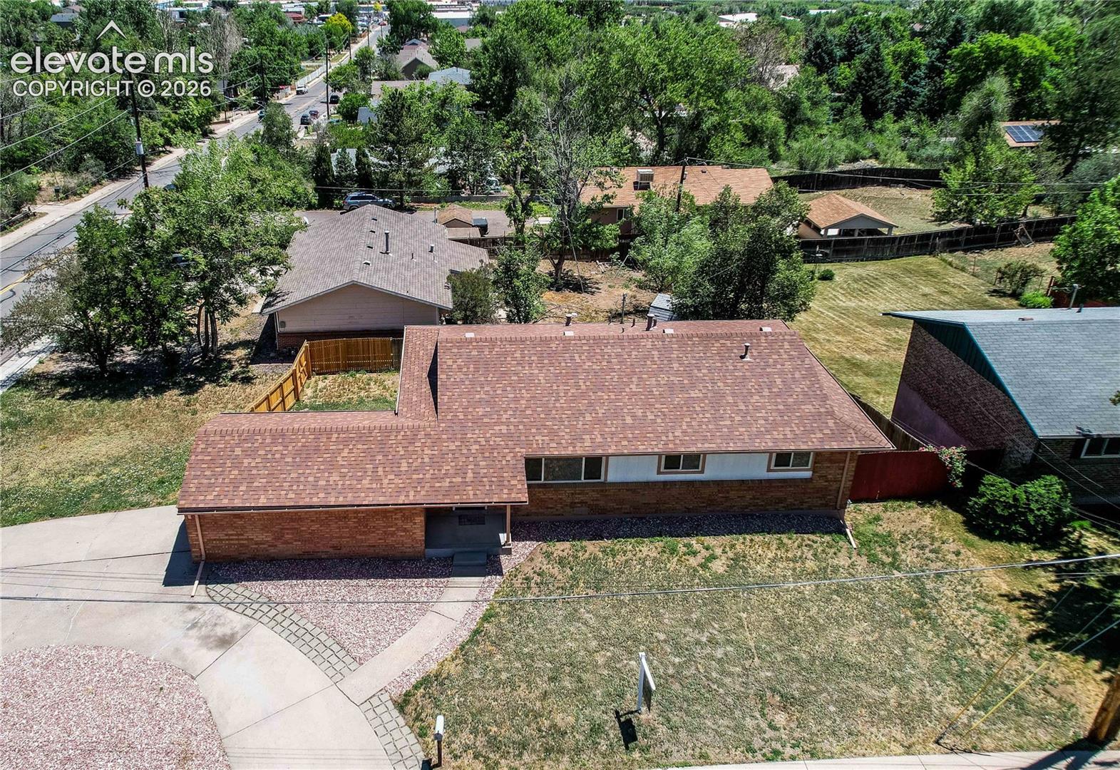 Single-story brick exterior residence featuring a composite shingle roof, attached garage, and paved concrete driveway