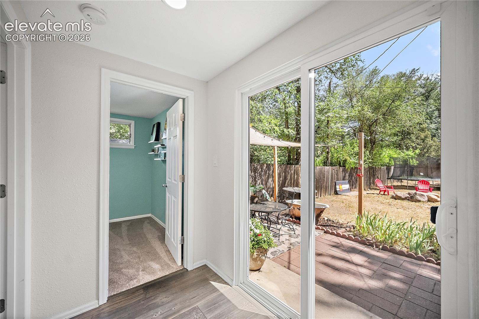 Sliding glass patio doors opening to a hardscaped patio area and private backyard