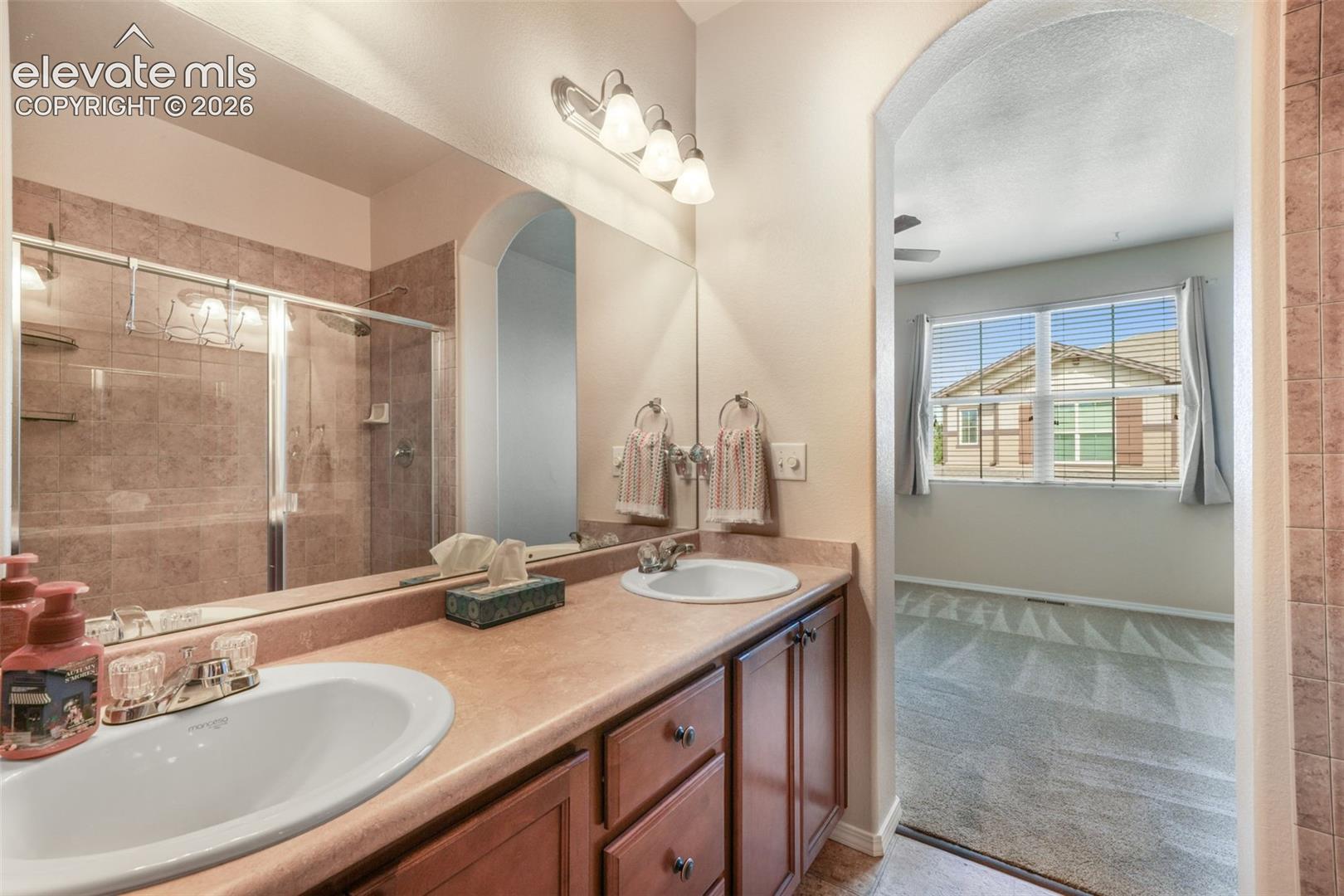 Dual vanity with integrated sinks, wood-finish cabinetry, and a full-width mirror