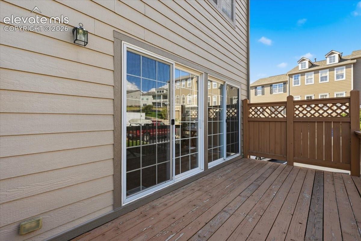 Wood deck with privacy lattice fencing, tan siding, and sliding glass doors