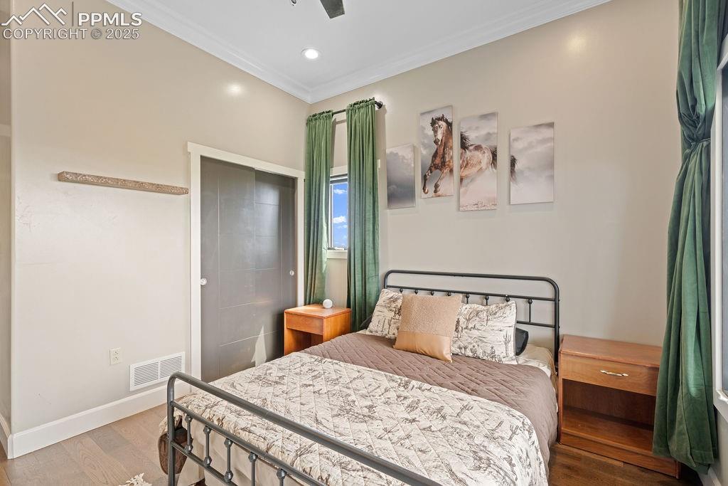 Bedroom with ornamental molding, wood finished floors, ceiling fan, and recessed lighting