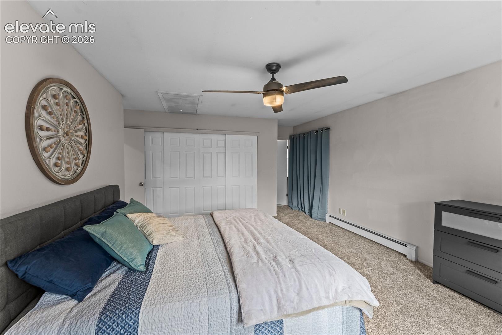Room featuring carpeting, a ceiling-mounted light fixture with a fan, and built-in closet cabinetry with sliding doors