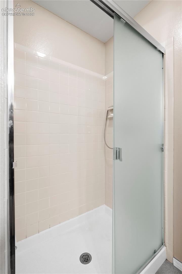Frosted glass shower enclosure with sliding door, featuring a tiled interior and a white shower pan with a chrome drain