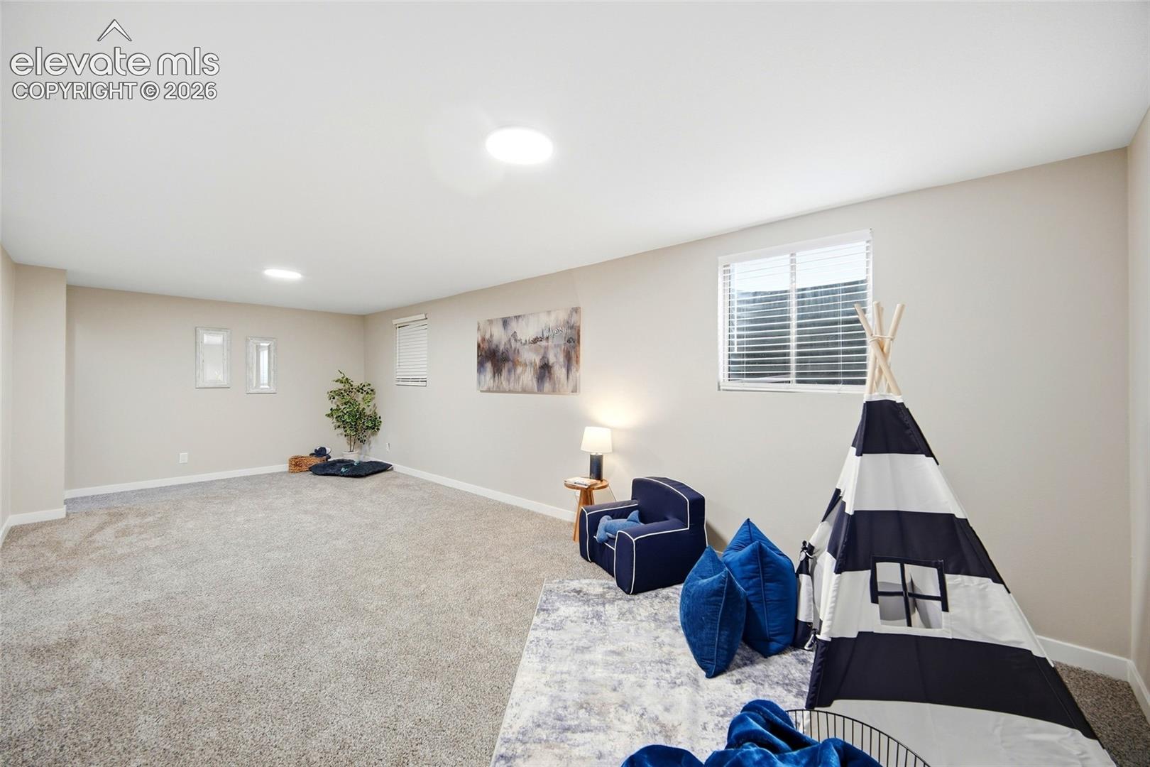 Spacious room featuring neutral carpeting, light-colored walls, recessed lighting, and a large window with blinds
