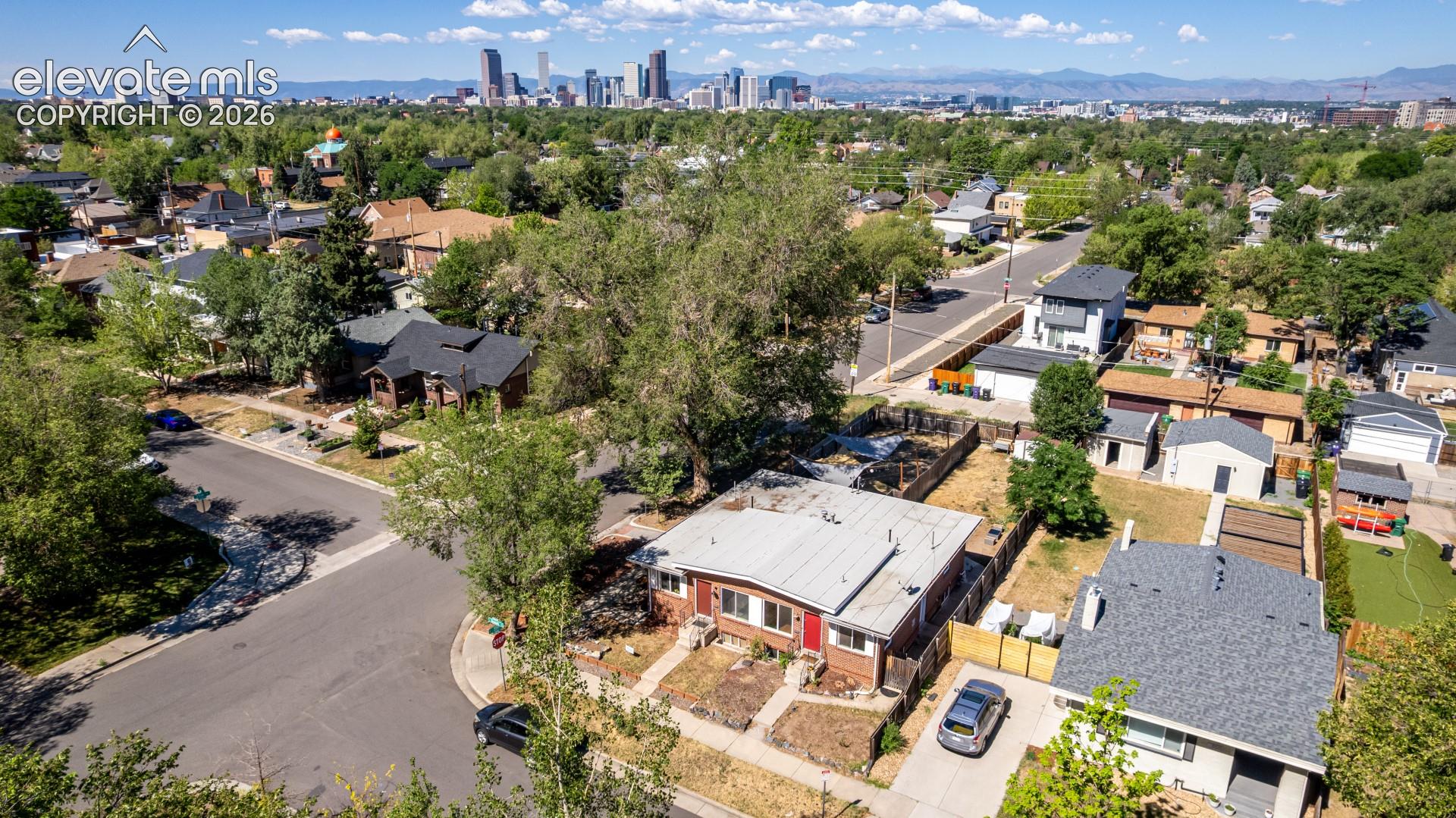 Spacious property featuring a large backyard with mature trees, a detached structure with a flat roof, and a gravel driveway
