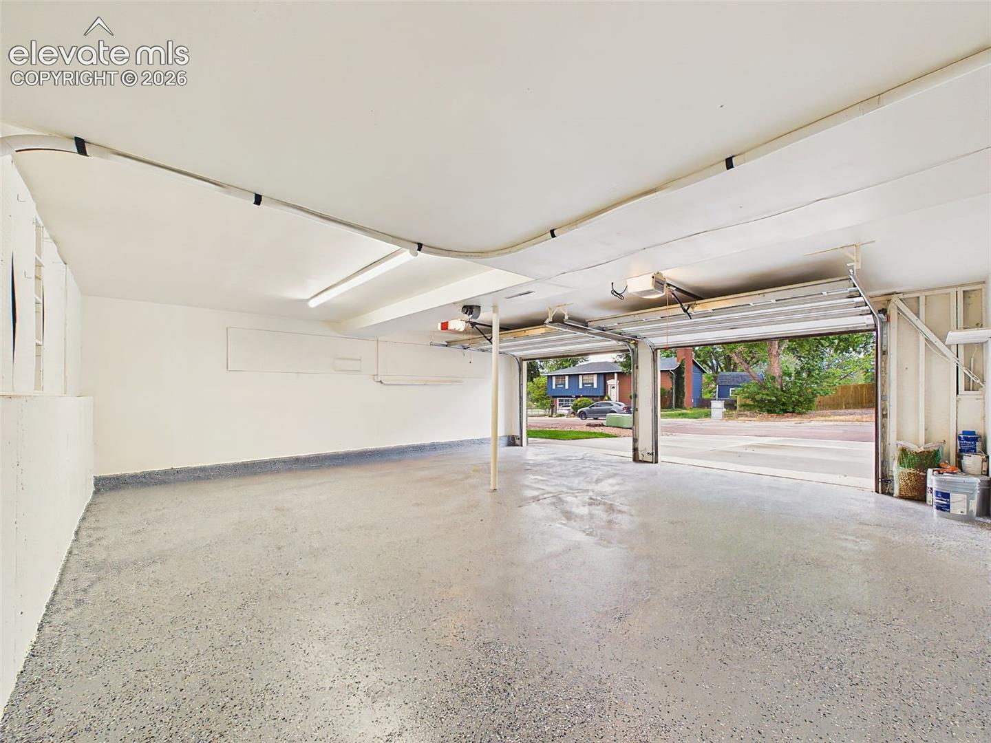 Spacious oversized two-car garage with durable epoxy-coated flooring, bright overhead lighting, and ample room for vehicles, storage, and workshop space.