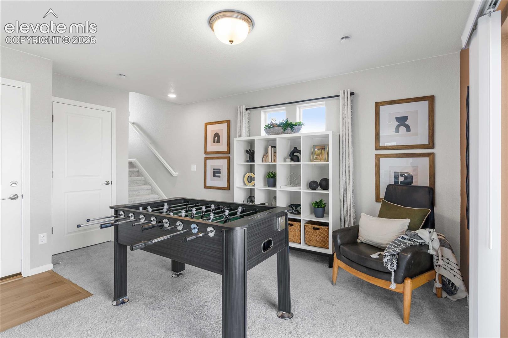 Recreation room featuring a foosball table, built-in shelving with decorative display space, wood-finish flooring, recessed ceiling lighting, and a seating area with wood-frame furniture and throw pillows
*photos of a model home*
