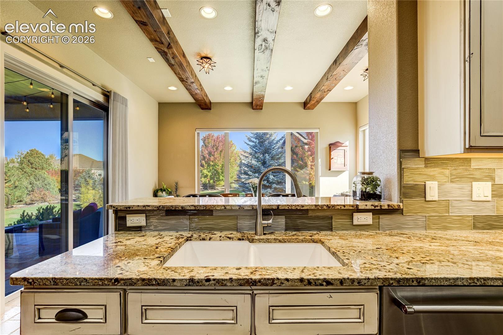 Dual sinks add exceptional function to the kitchen, with granite countertops, detailed cabinetry + an open view toward the light-filled garden room creating a seamless connection between meal preparation and gathering spaces.