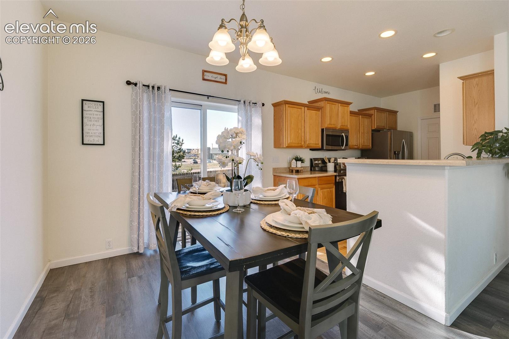 Wood-finish flooring, sliding glass door, recessed lighting, and a kitchen island with stone-finish countertop