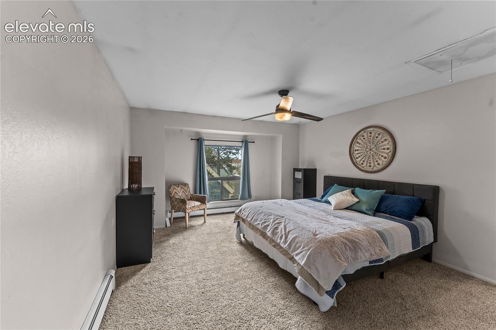 Neutral interior featuring wall-to-wall carpeting, a recessed window nook, and a multi-blade ceiling fan with integrated lighting