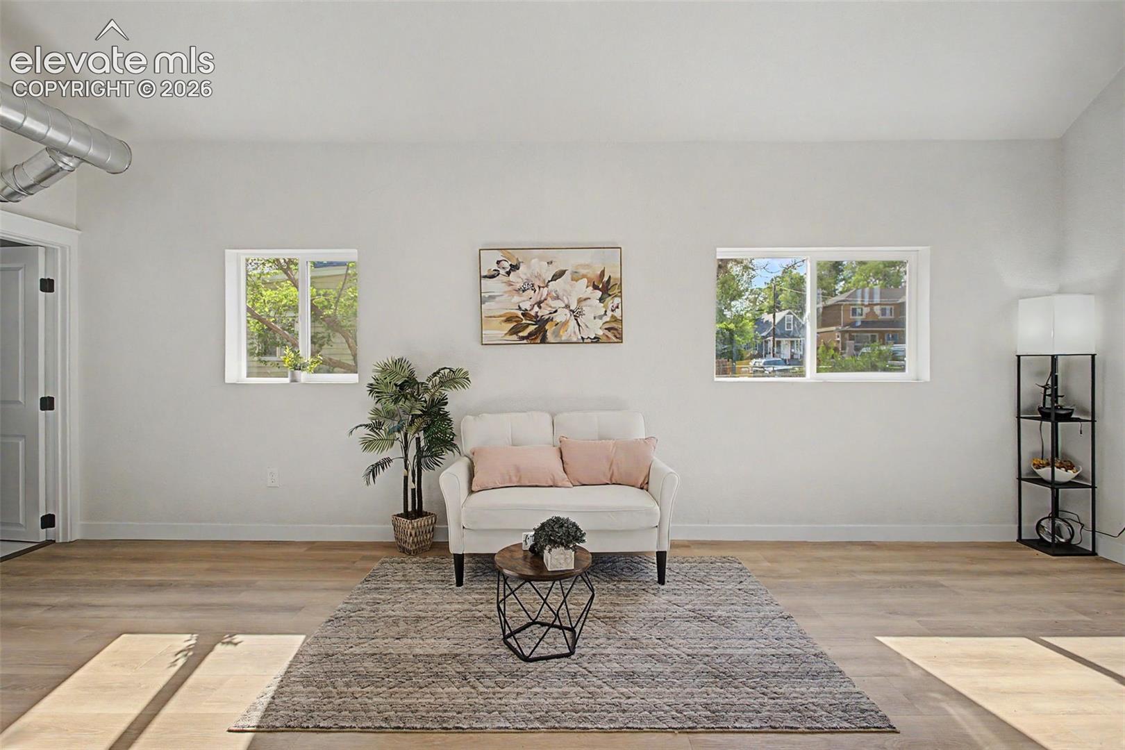Spacious interior featuring wood-finish flooring, white walls, and two windows